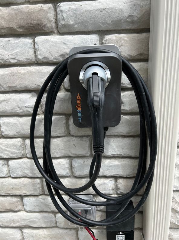 Un chargeur de voiture électrique est fixé à un mur de briques.