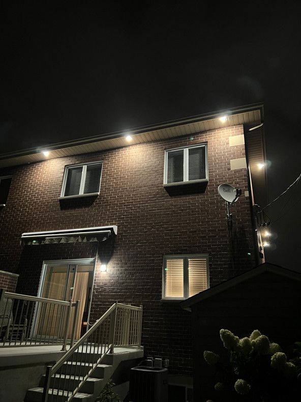 L'arrière d'une maison en brique est éclairée la nuit.