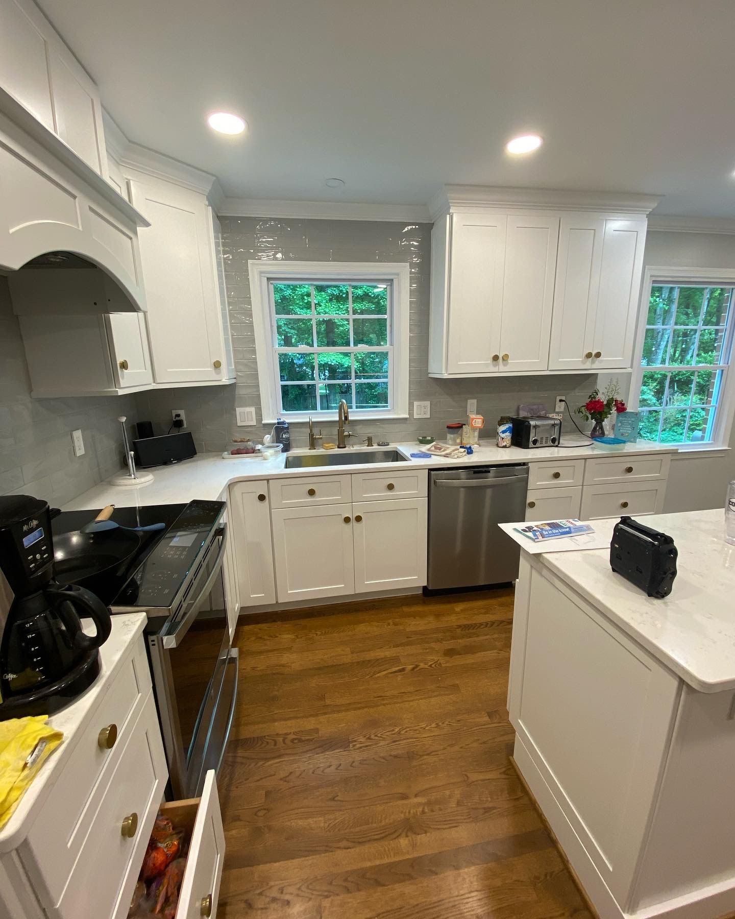 White kitchen with cabinetry, stainless steel appliances, and wood flooring.