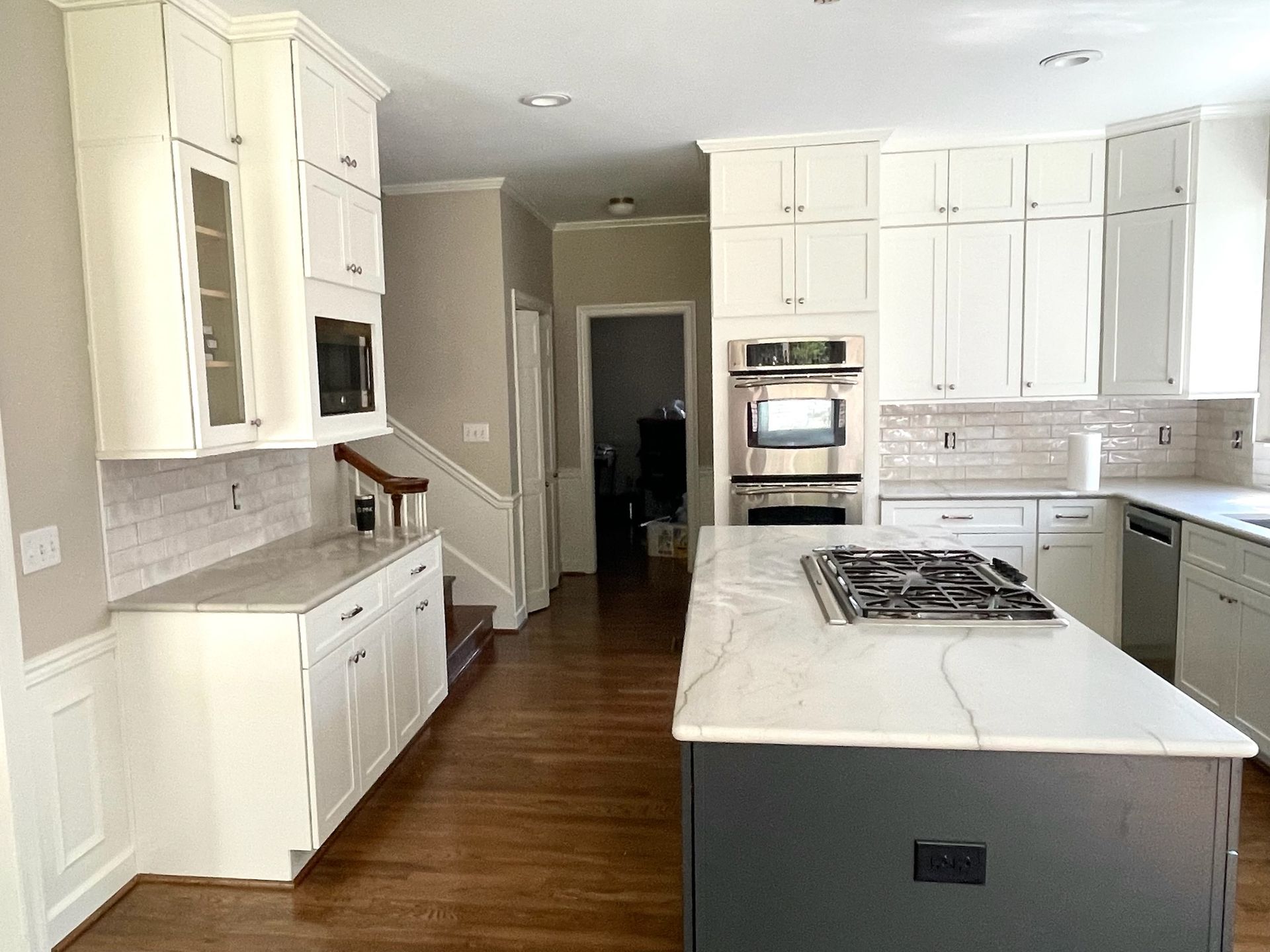 White kitchen with gray island, stainless steel appliances, and wooden floors.