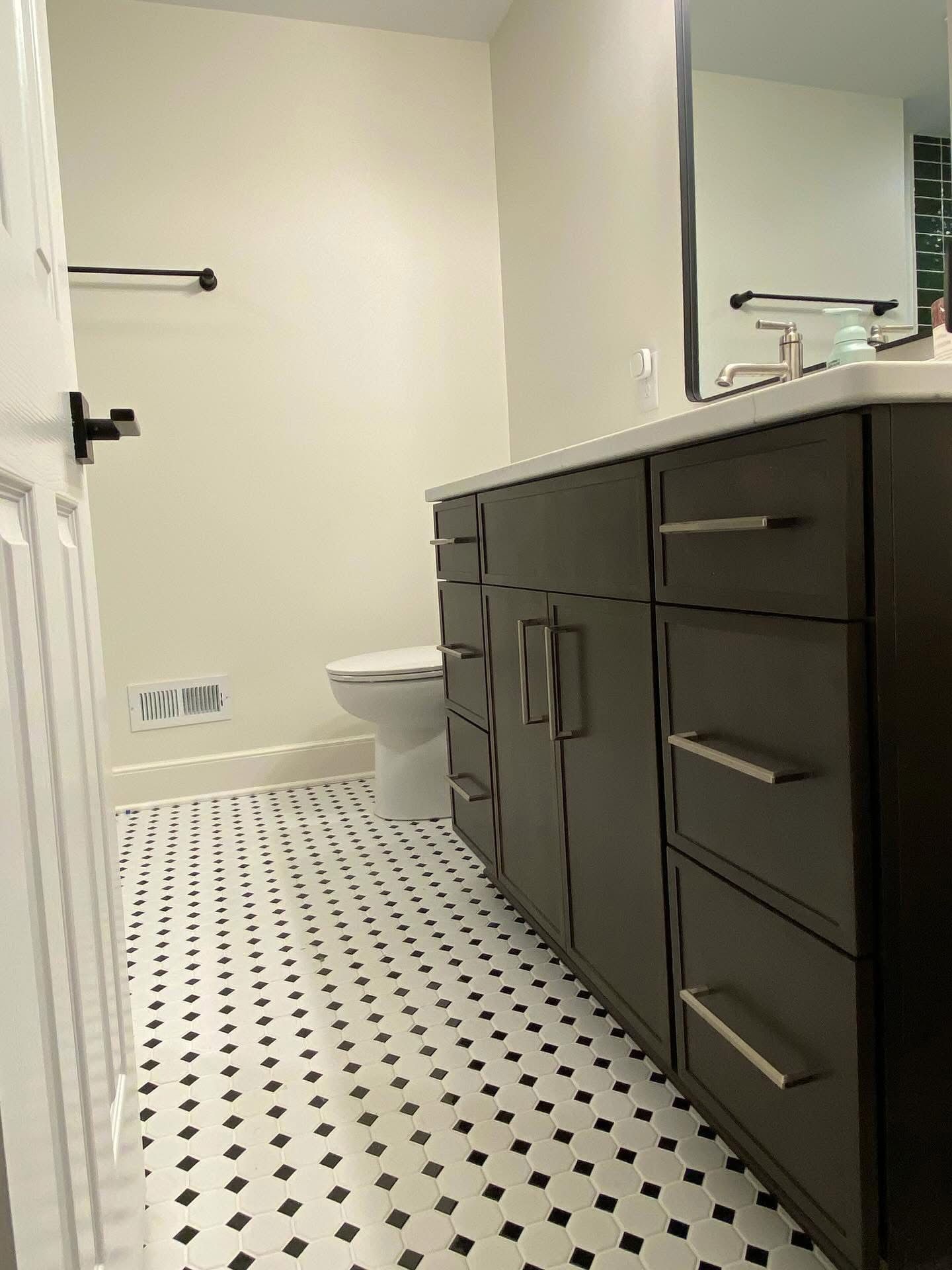 Bathroom with dark cabinetry, patterned floor, and white walls.