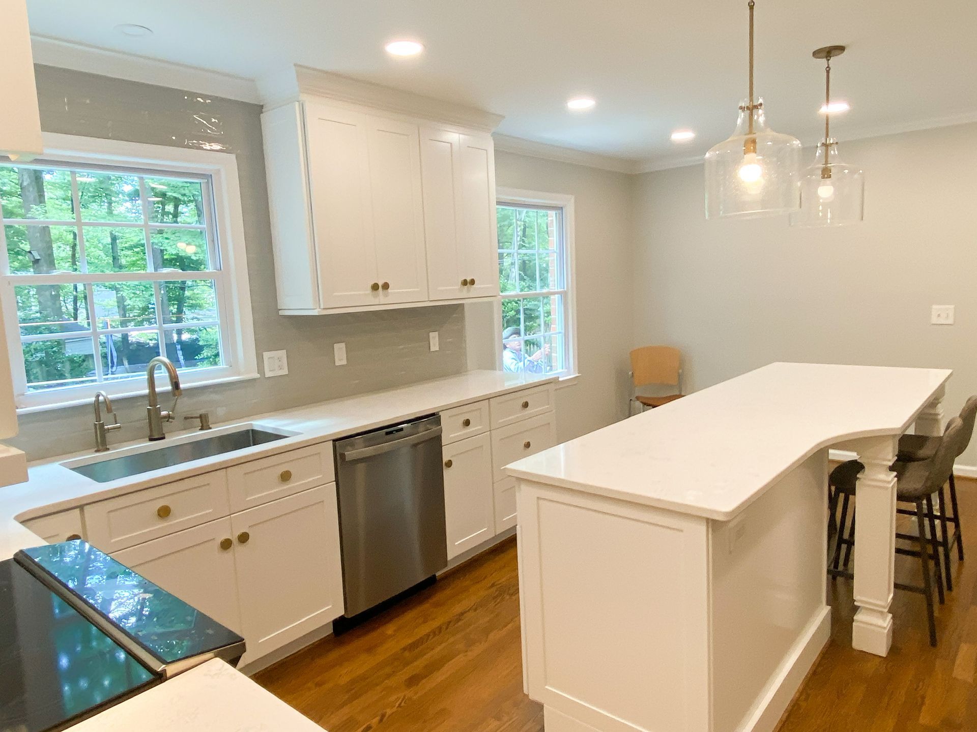 White kitchen with island, cabinets, stainless steel appliances, and two windows.