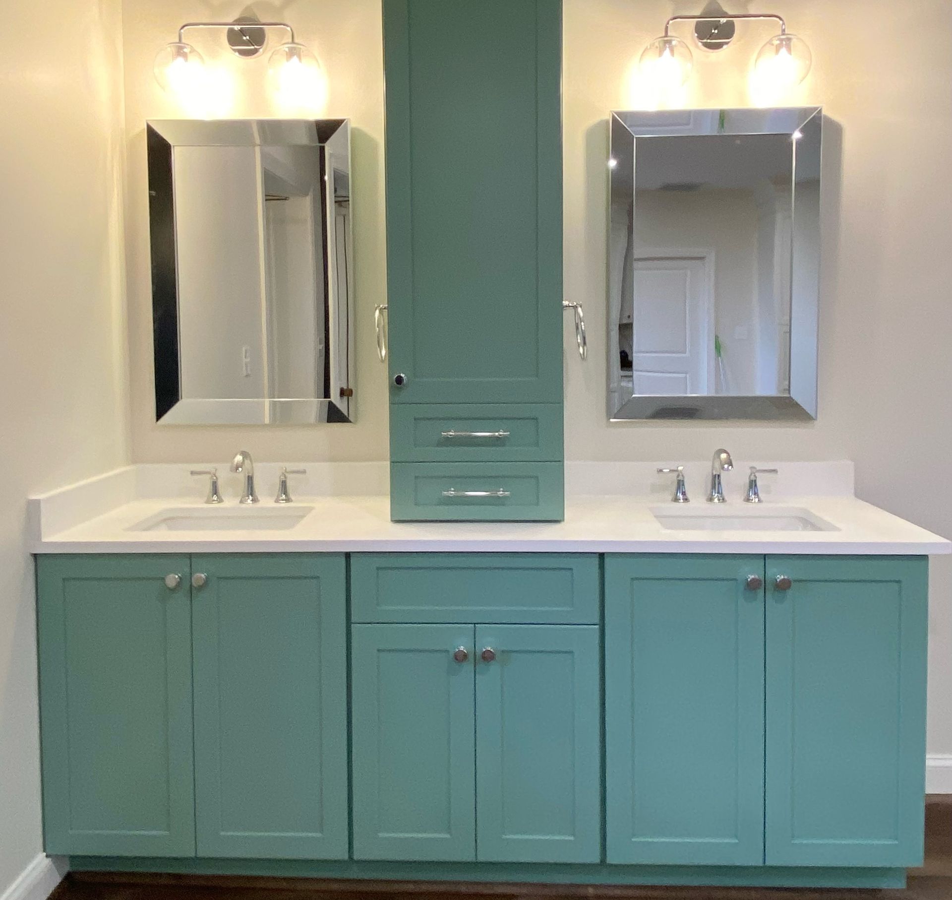 Aqua bathroom vanity with two sinks, mirrors, and a tall cabinet.