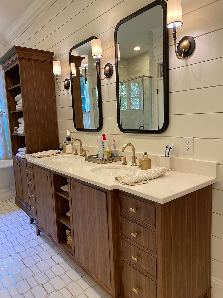 Bathroom with dark wood vanity, white countertop, two mirrors, and gold fixtures.