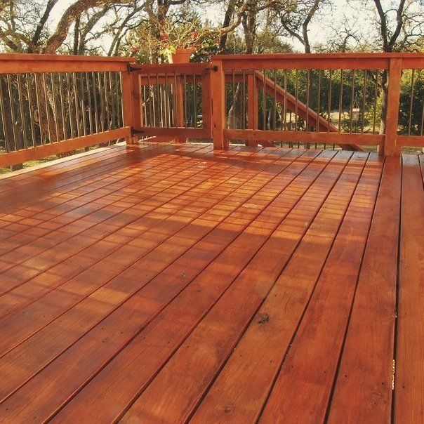 A wooden deck with a railing and trees in the background
