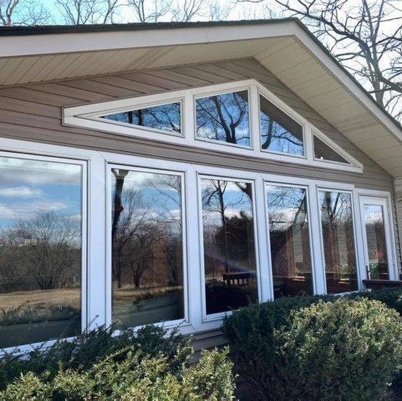 A house with a lot of windows and trees reflected in the windows