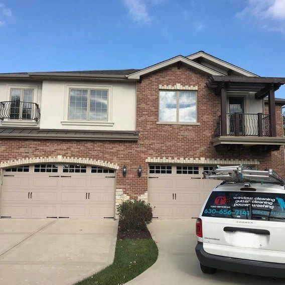 A white car is parked in front of a large brick house