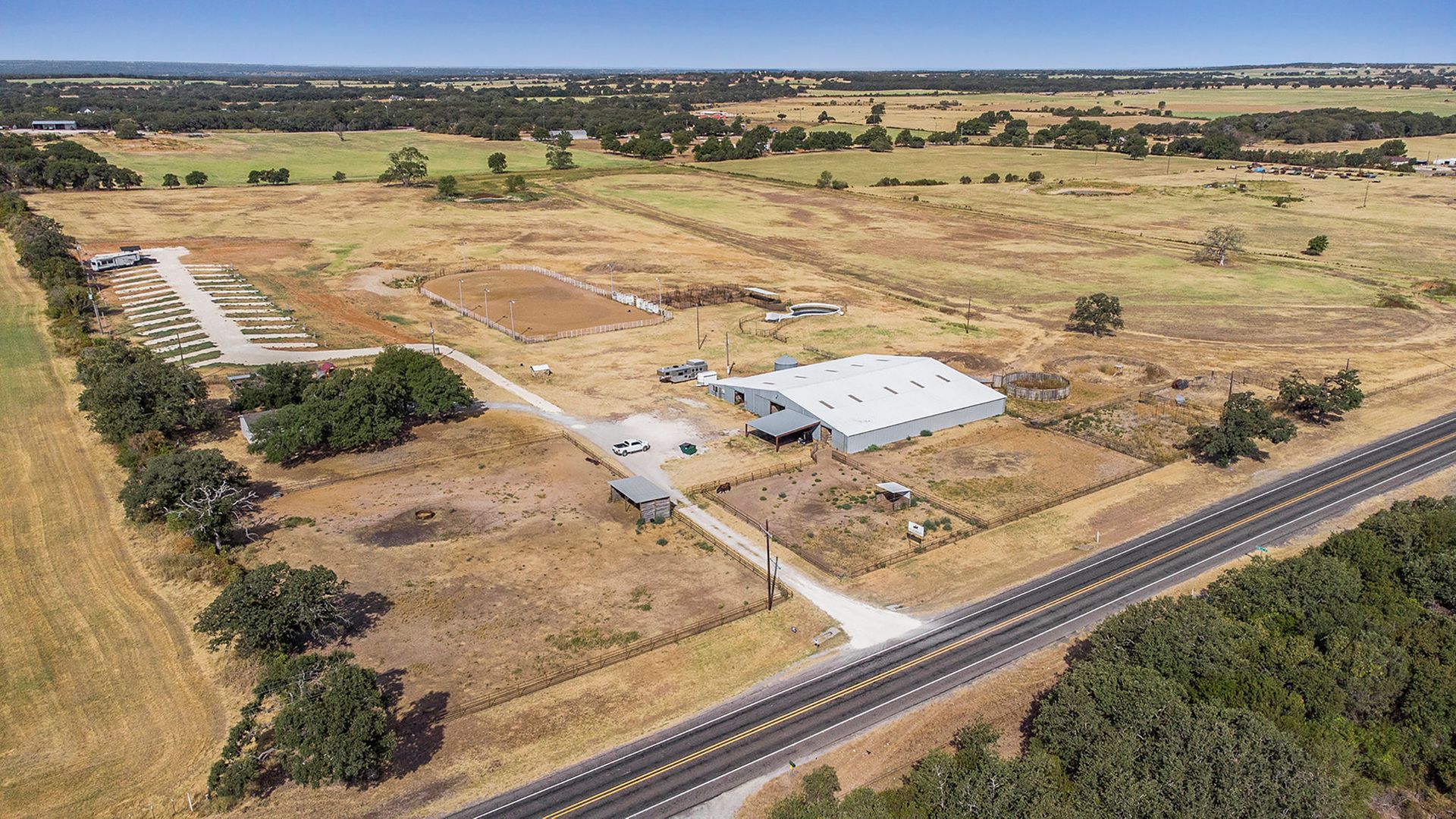 An aerial view of a large farm surrounded by trees and a highway.