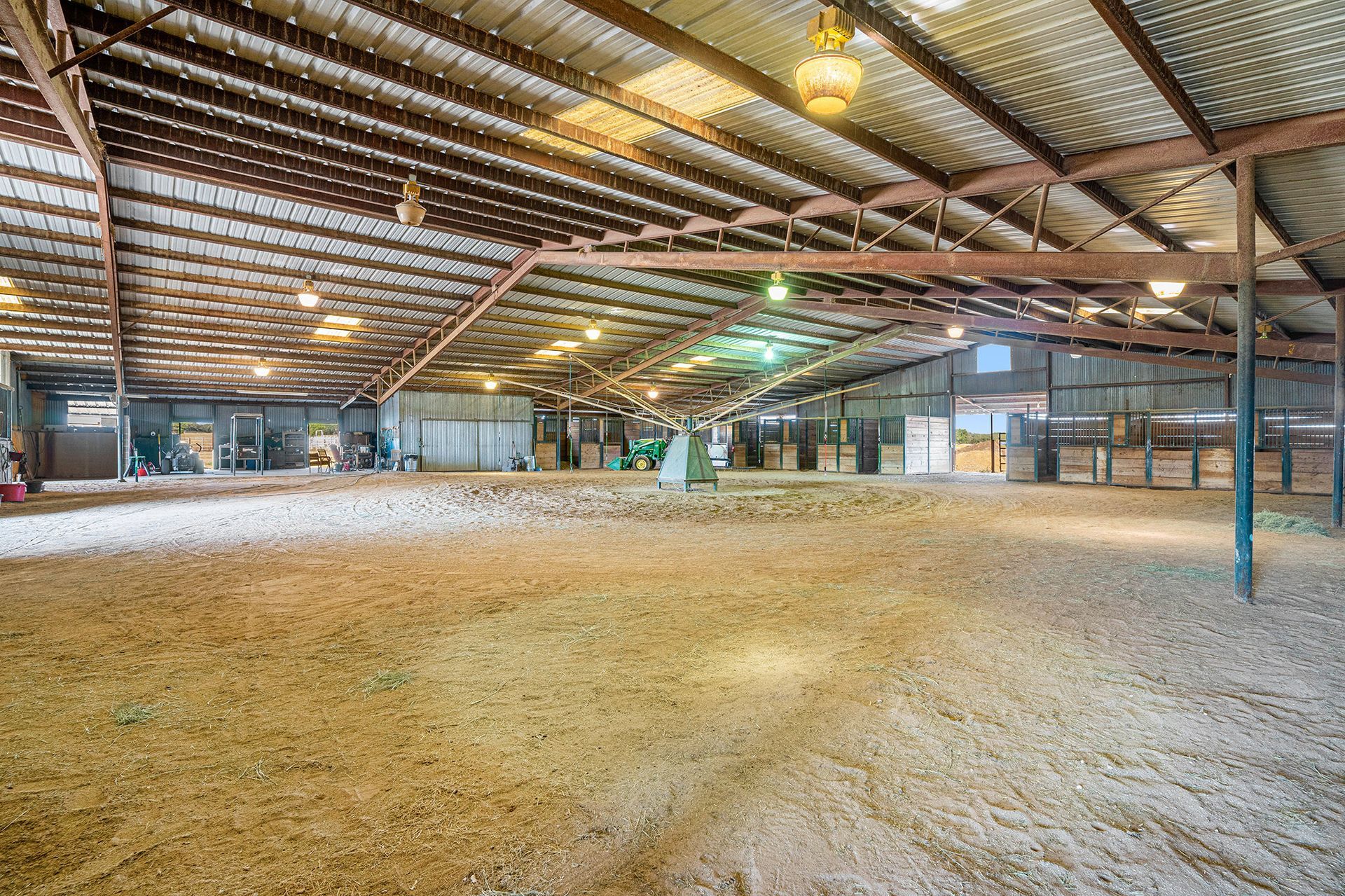A large empty barn with a lot of dirt in it.
