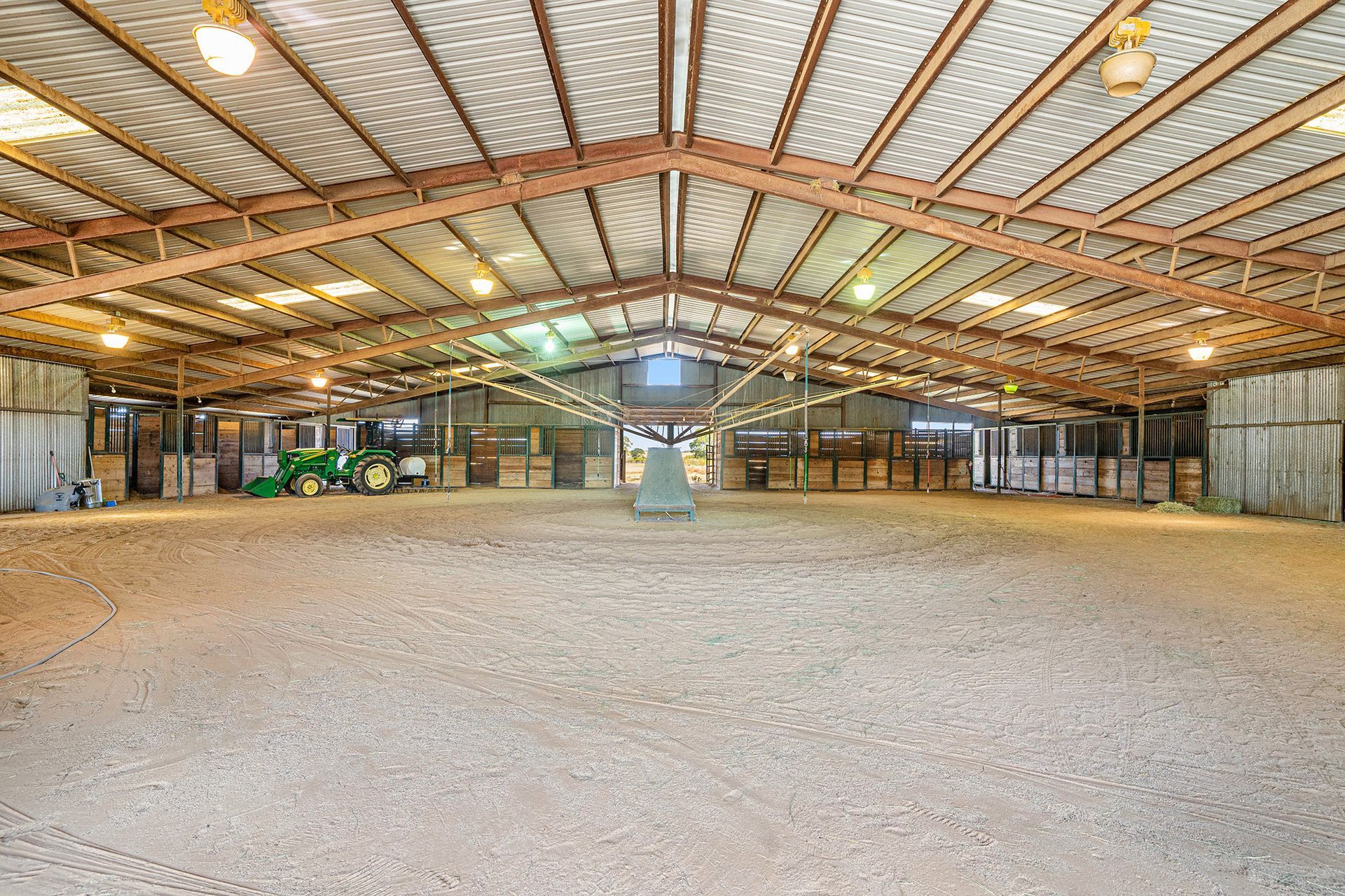 A large empty barn with a tractor parked inside of it.