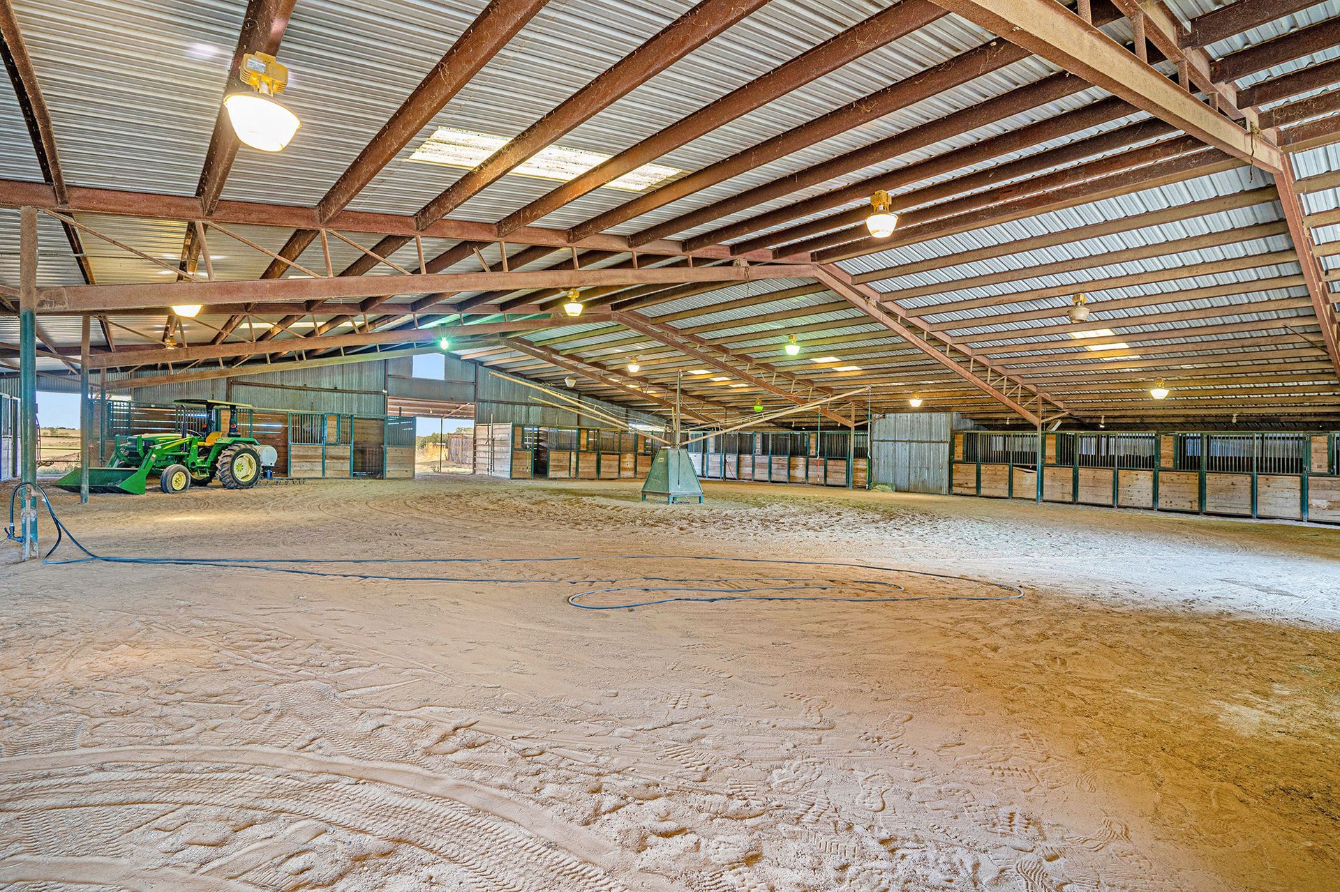 A large empty barn with a tractor parked inside of it.