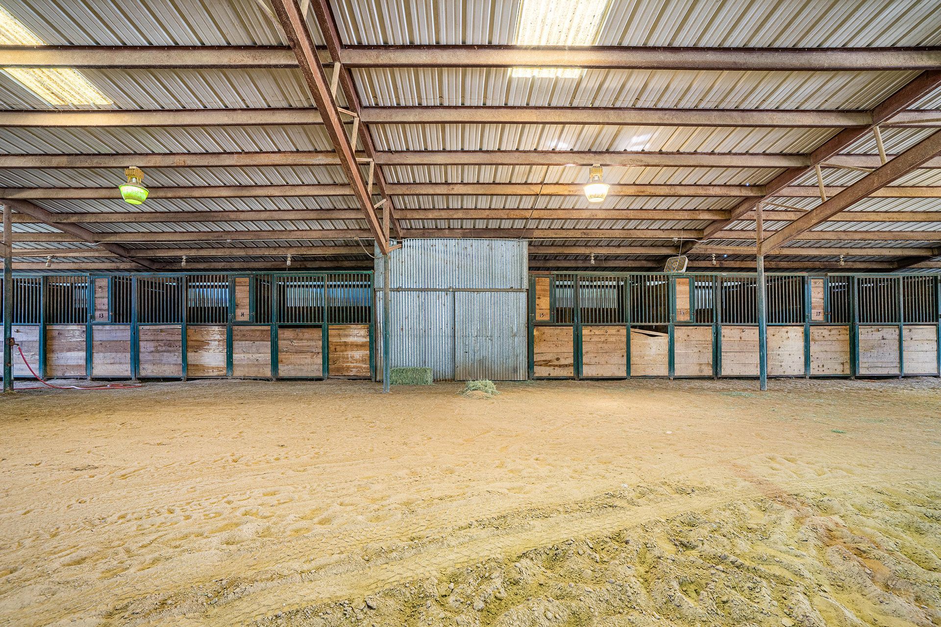 A large empty stable with a lot of hay in it.