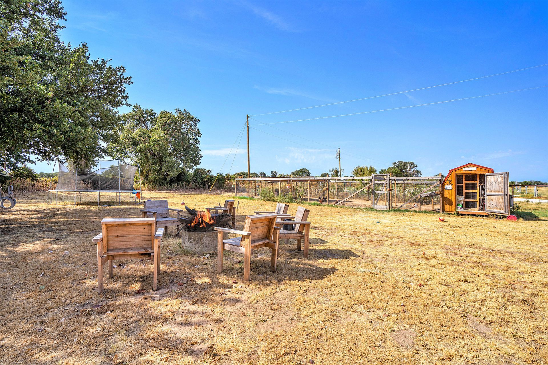 A group of chairs are sitting in a field next to a fire pit.