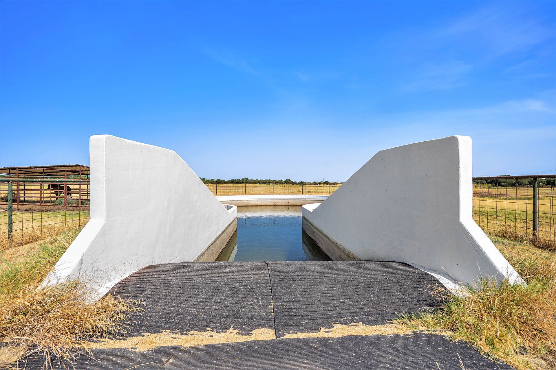 A white bridge over a body of water in a field
