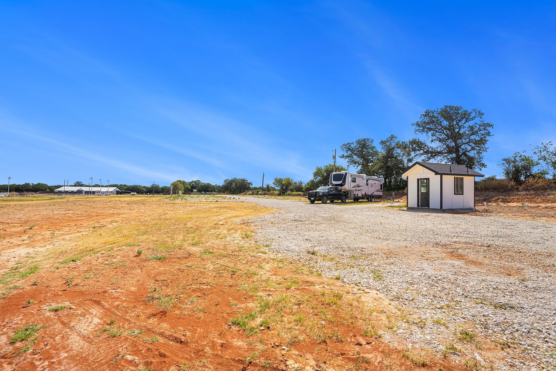 A small white house is sitting in the middle of a dirt field.
