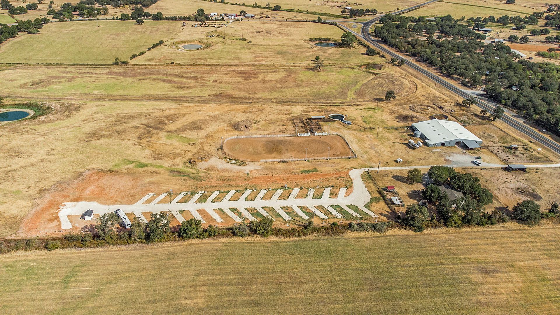 An aerial view of a large field with a lot of trees and a road.