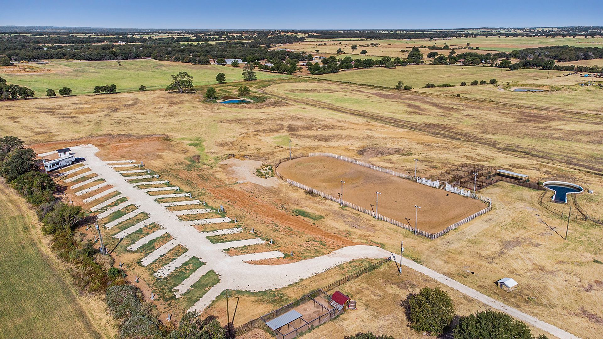 An aerial view of a ranch with a lot of dirt and trees.