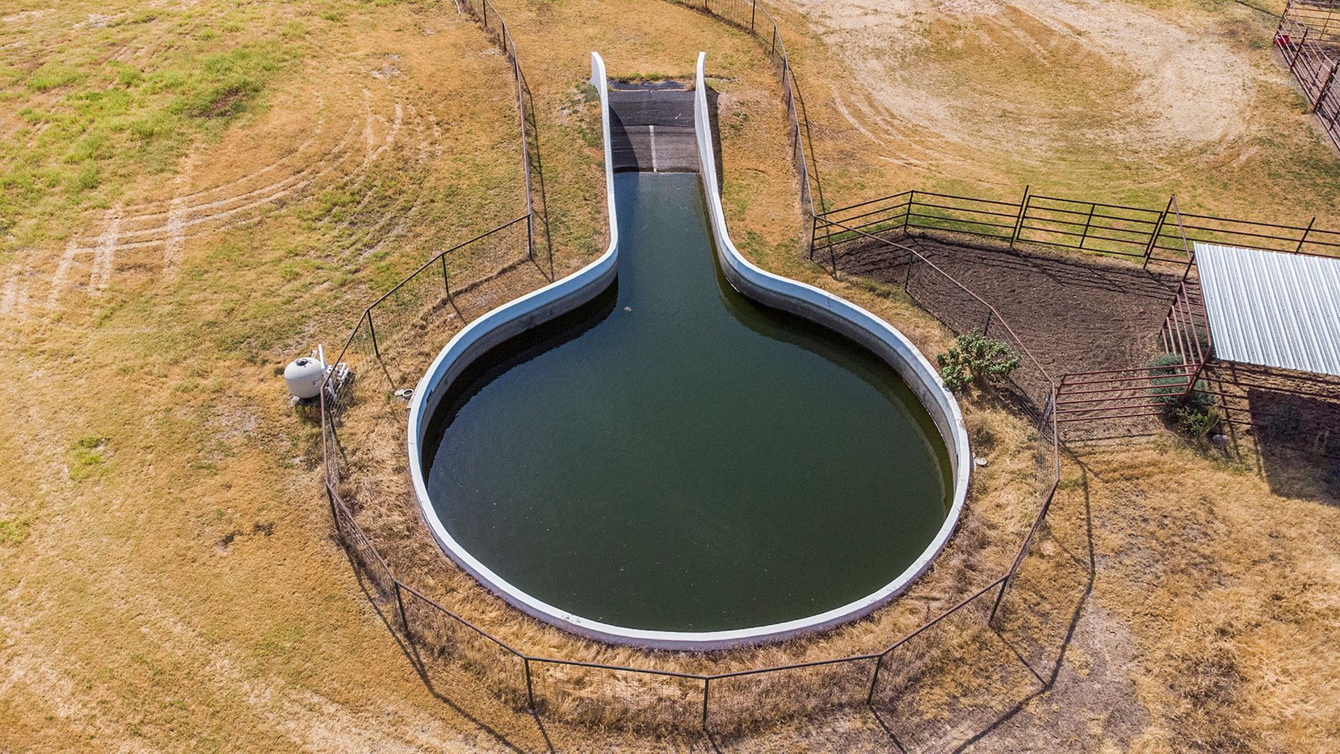 An aerial view of a large pond in the middle of a field.