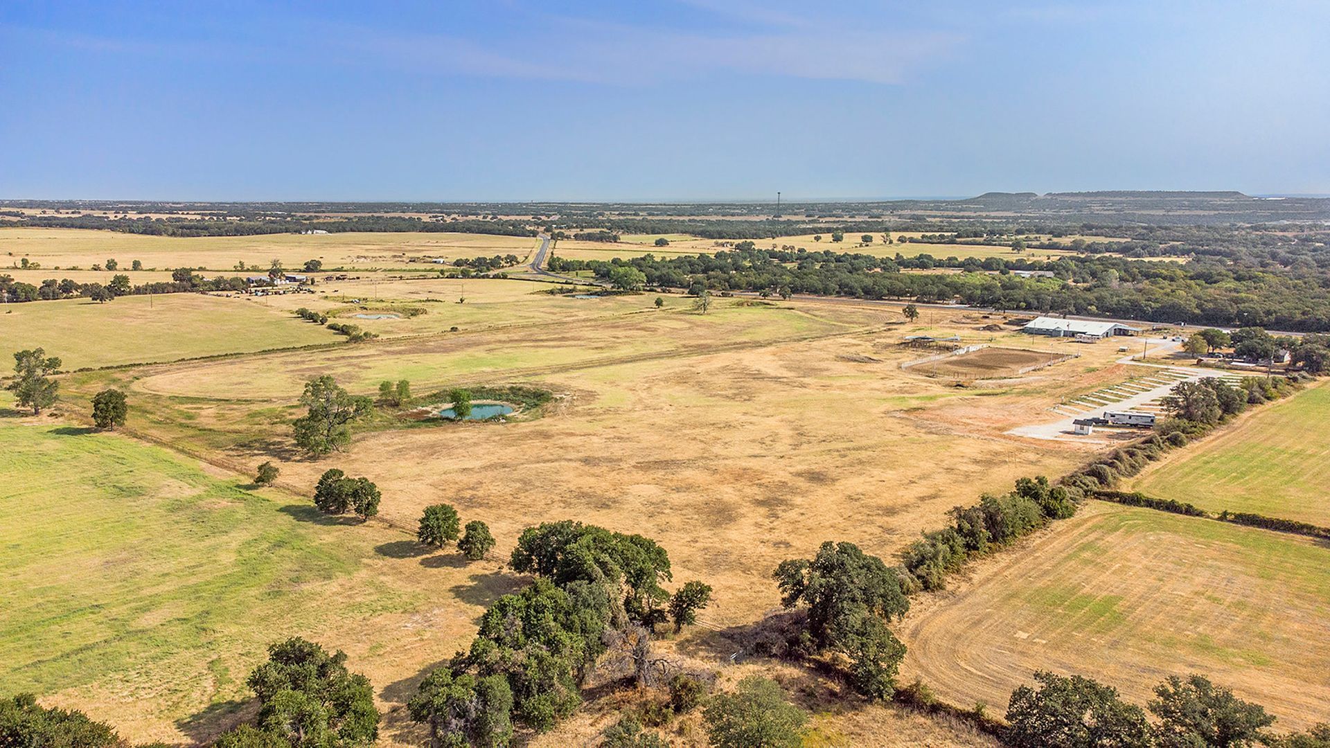 An aerial view of a lush green field with trees and grass.