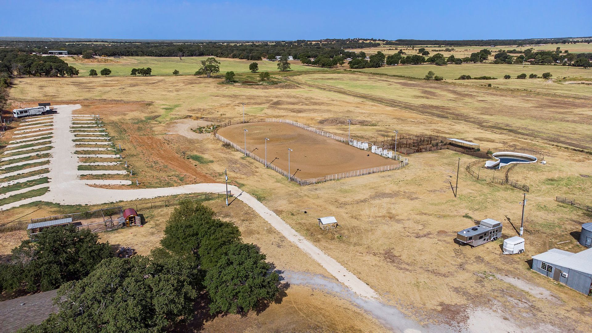 An aerial view of a large dry grass field with a dirt road going through it.