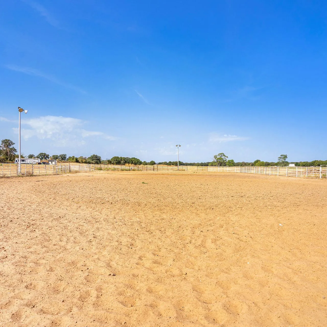 A horse is standing in a dirt field next to a fence.