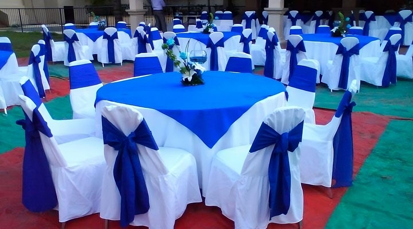 Una mesa con un mantel azul y sillas blancas