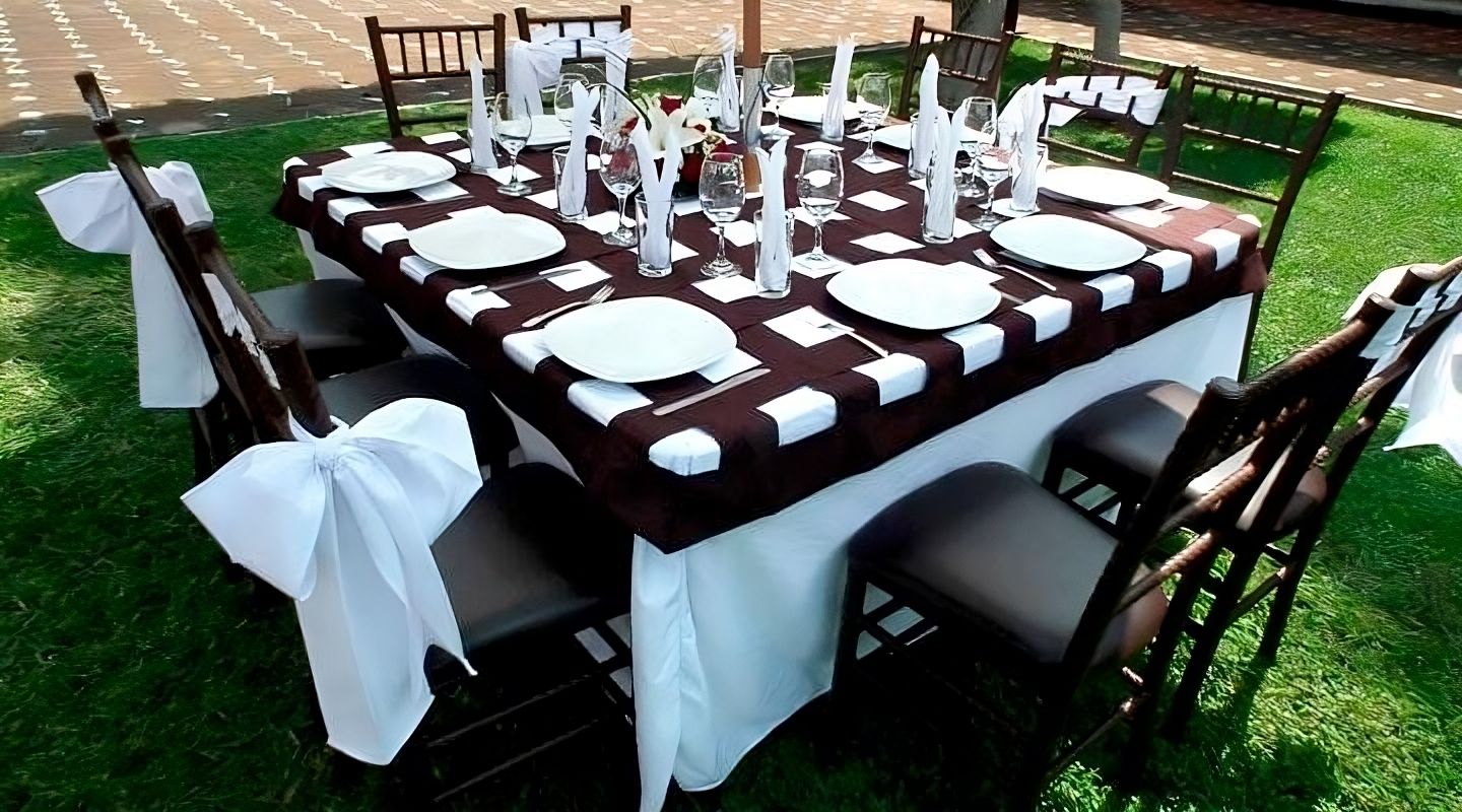 Una mesa con un mantel a rayas rojas y blancas y sillas blancas