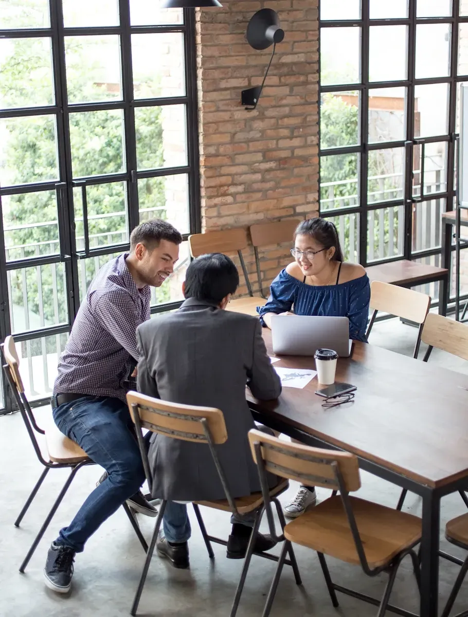 Drie mensen werken samen aan een tafel in een café samen hebben zij een meeting op een professionele wordpress website te laten maken