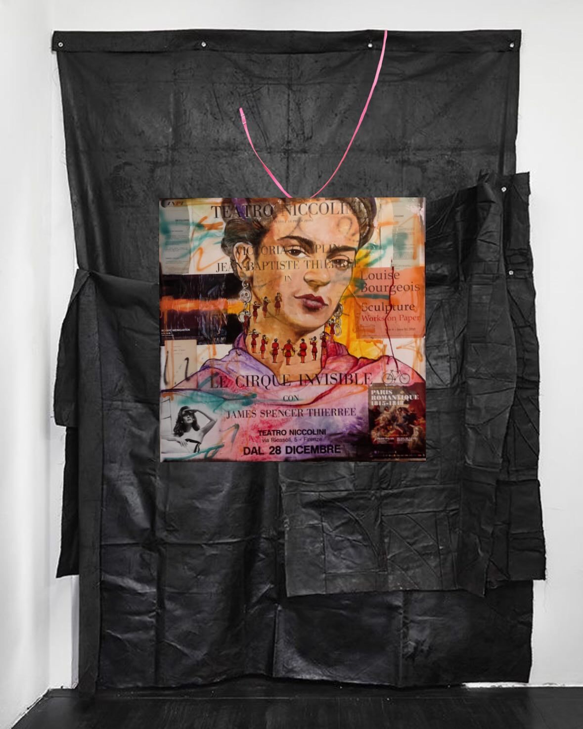 Un collage con un ritratto di Frida Kahlo al centro, su un grande sfondo nero stropicciato, appeso a una parete.