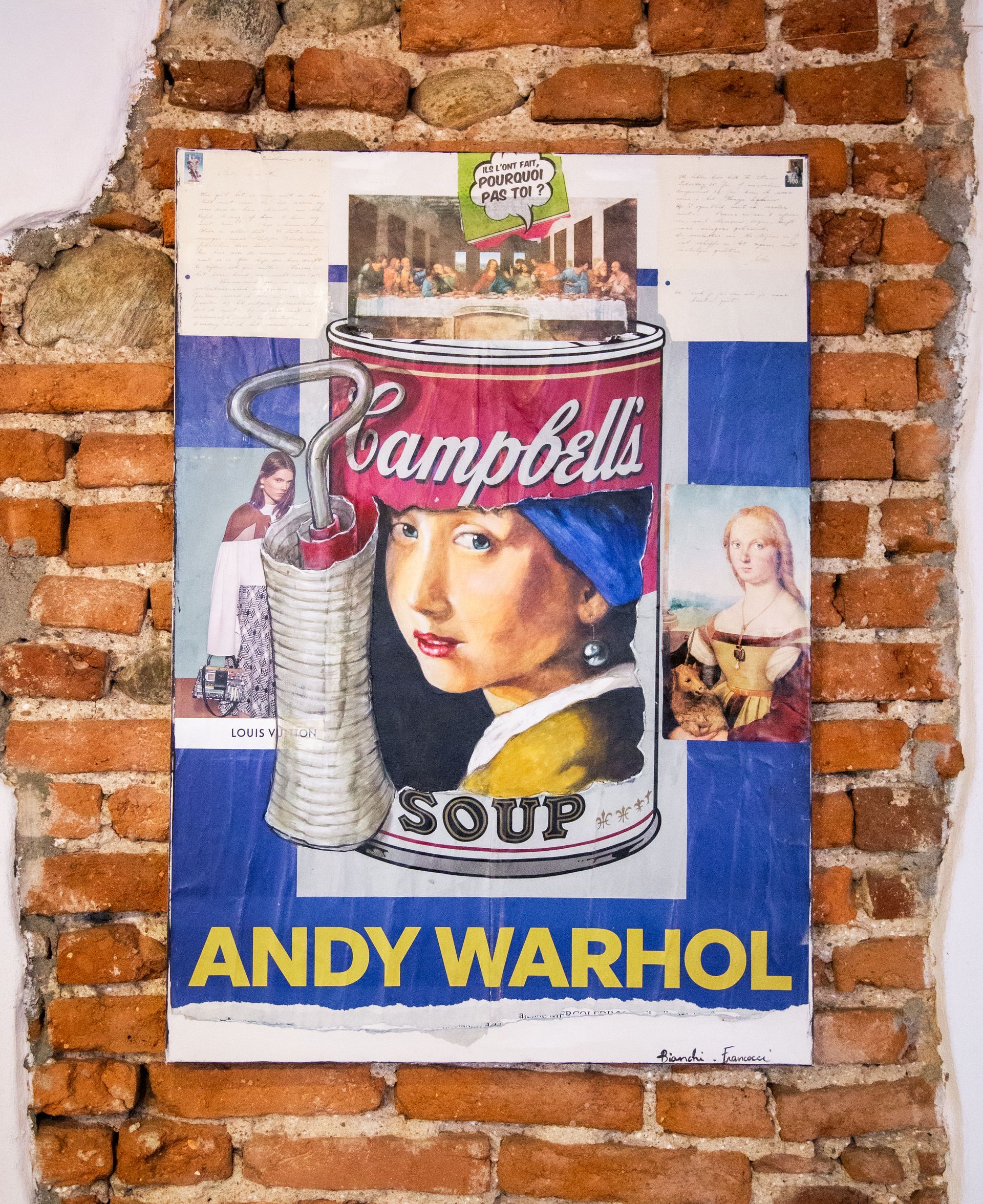 Una stampa artistica di Andy Warhol raffigurante una lattina di zuppa con un ritratto dipinto, esposta su un muro di mattoni a vista.