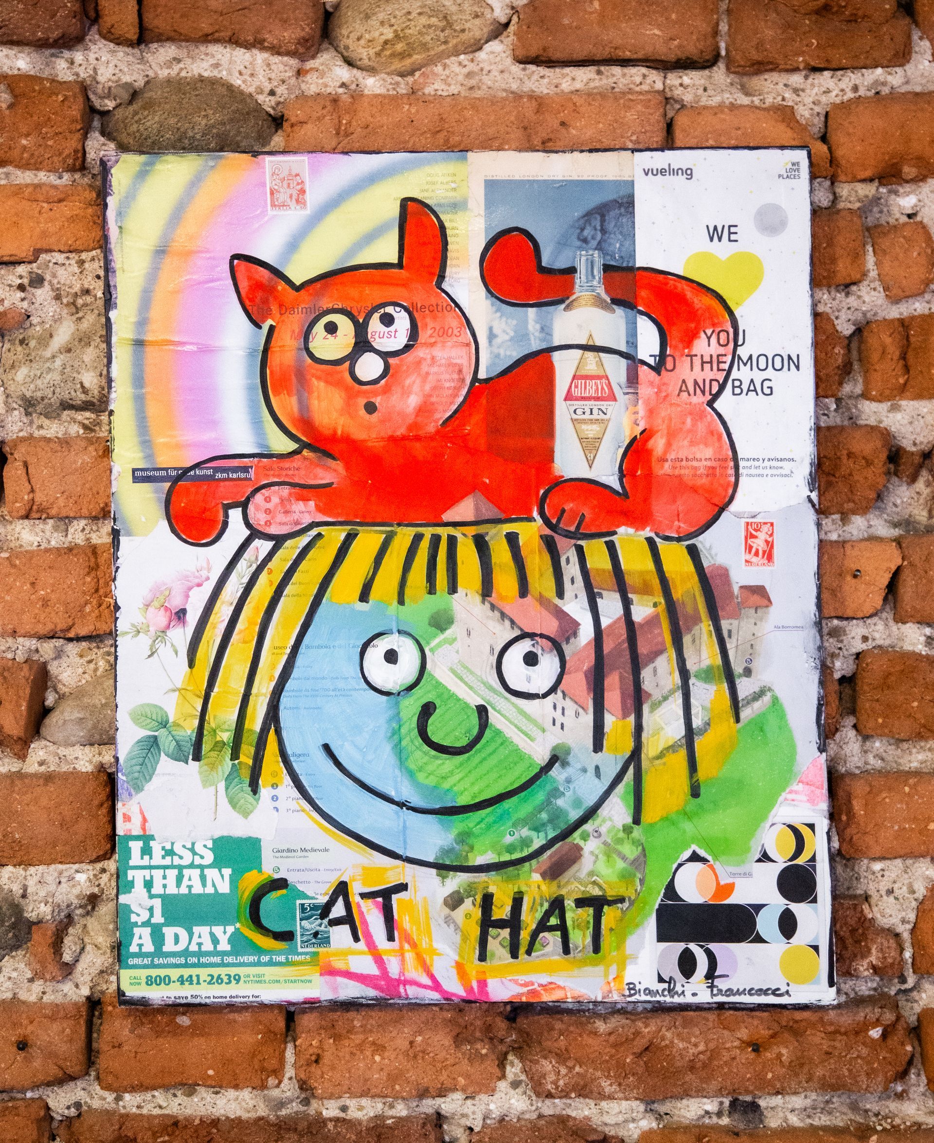 Un'opera d'arte a tecnica mista su un muro di mattoni raffigura un gatto arancione che riposa sulla testa di una persona. Sotto la figura si legge la scritta 