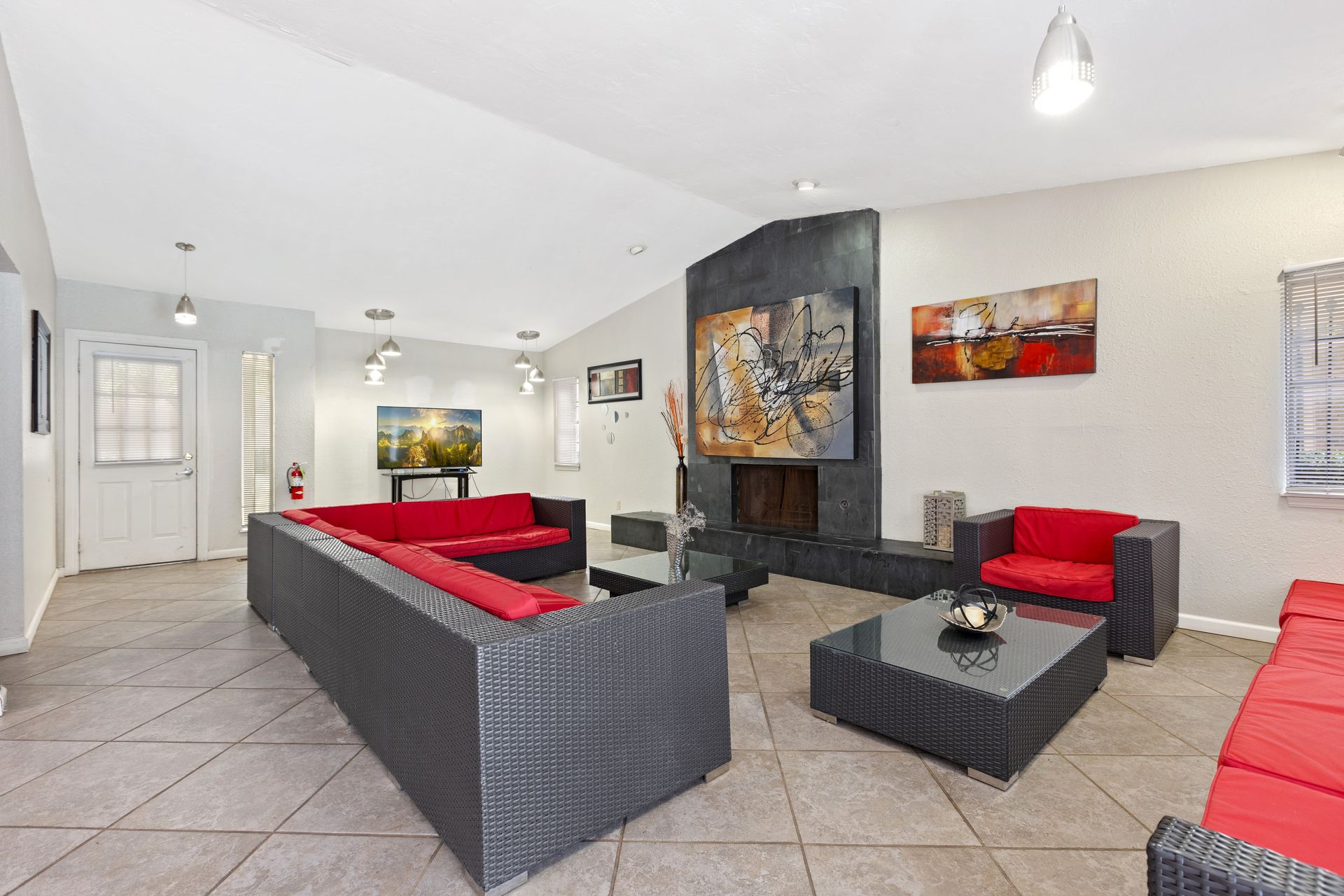 Modern living room with red and black furniture, fireplace, and artwork.