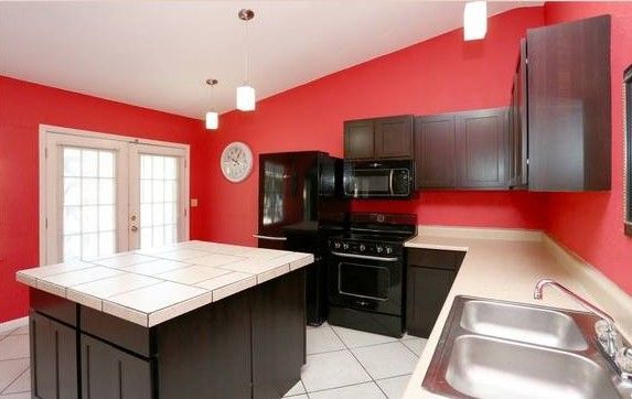 Red kitchen with dark cabinets, stainless steel sink, and island.