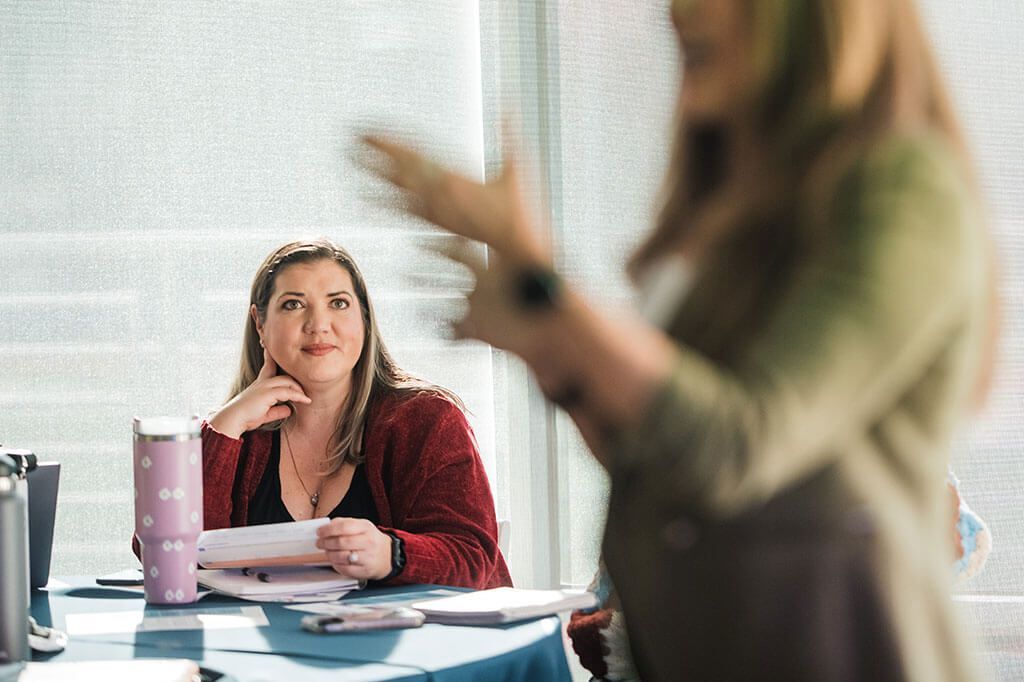 A woman is sitting at a table talking to another woman.