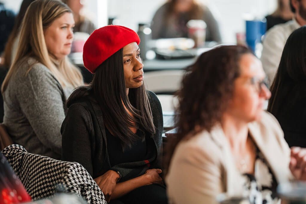 A woman wearing a red beret is sitting in a crowd of people.