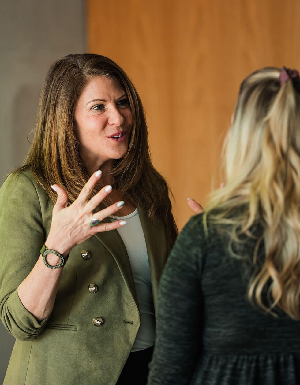 A woman in a green jacket is talking to another woman.