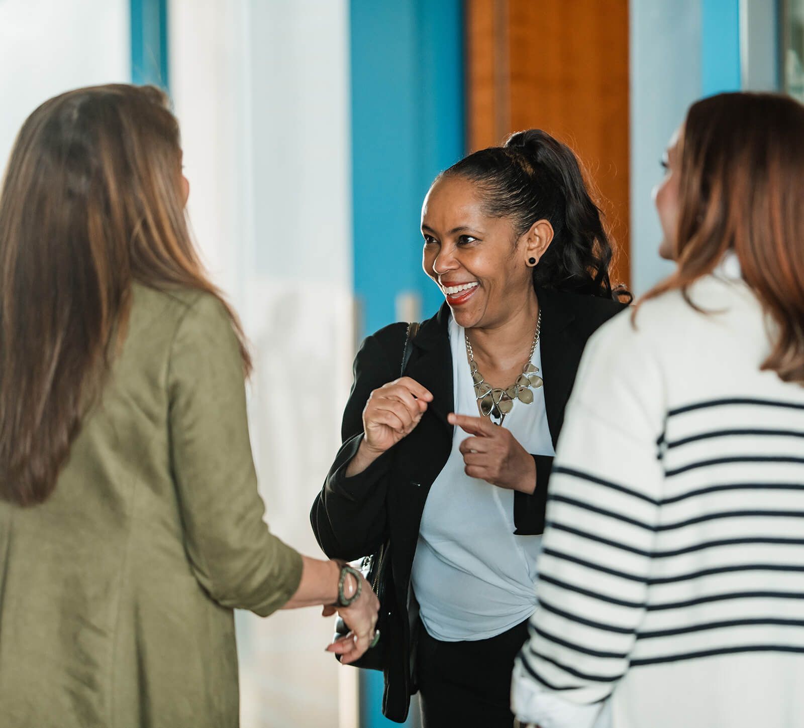 Three women are standing next to each other and talking