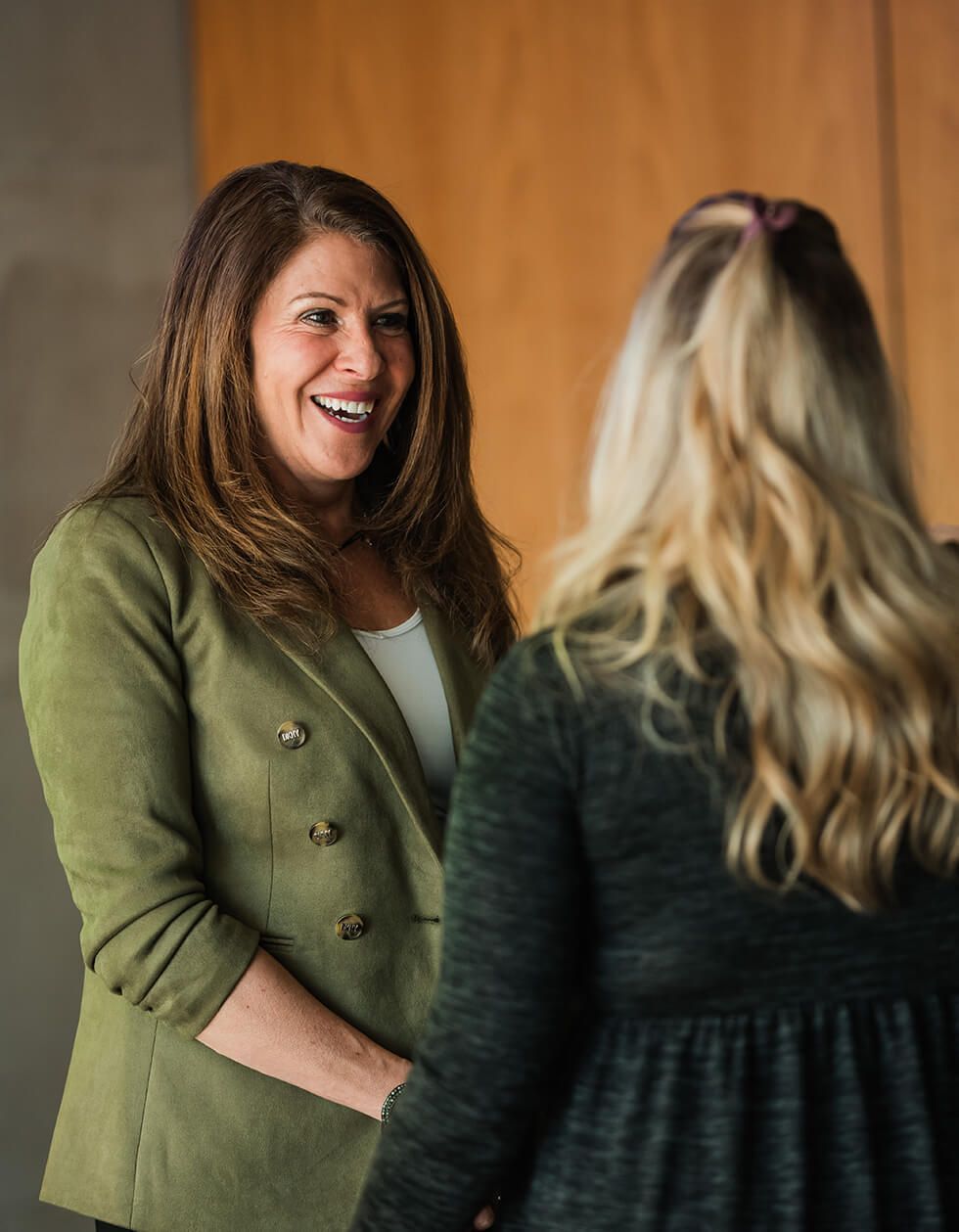 A woman in a green jacket is talking to another woman.