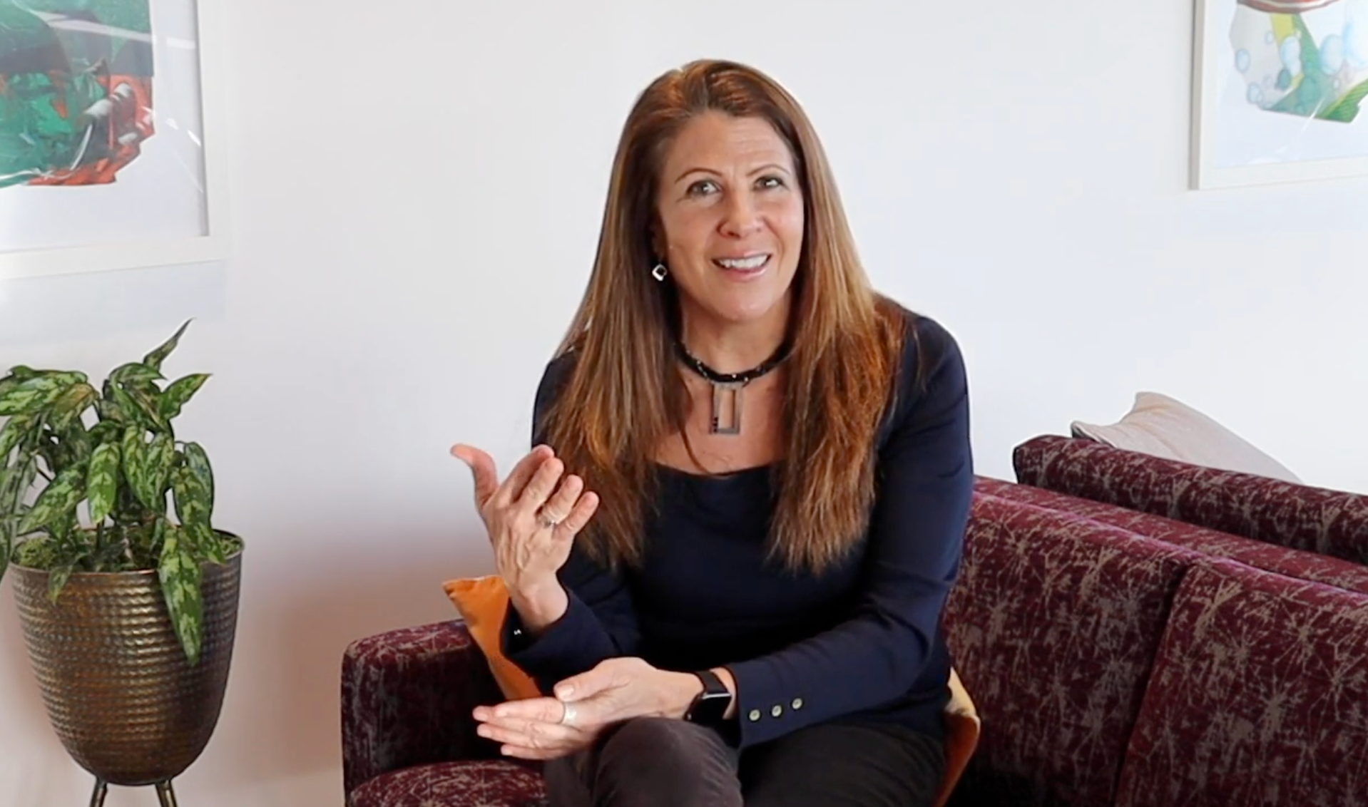 A woman is sitting on a couch talking to someone.