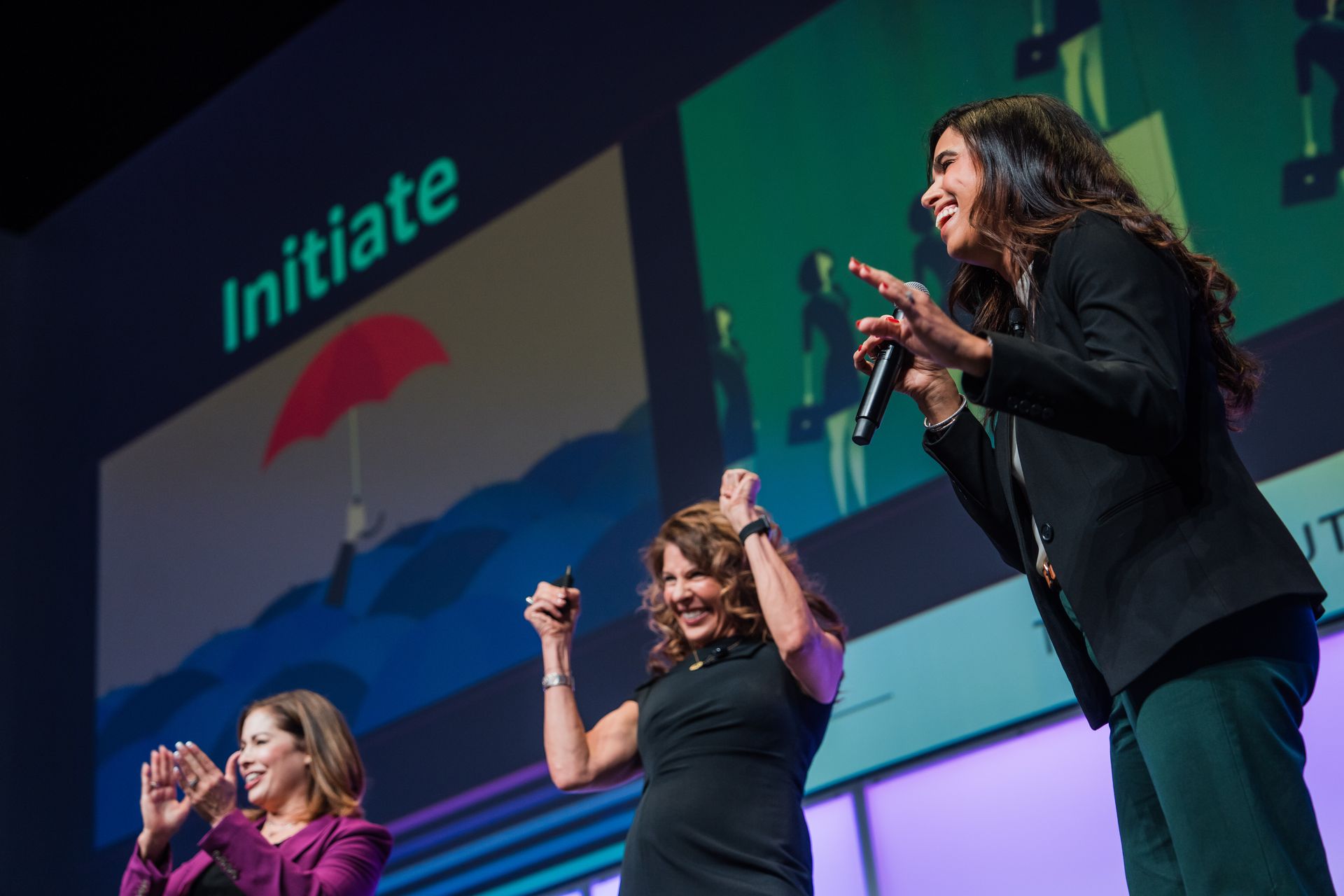 Three women are standing on a stage holding microphones.