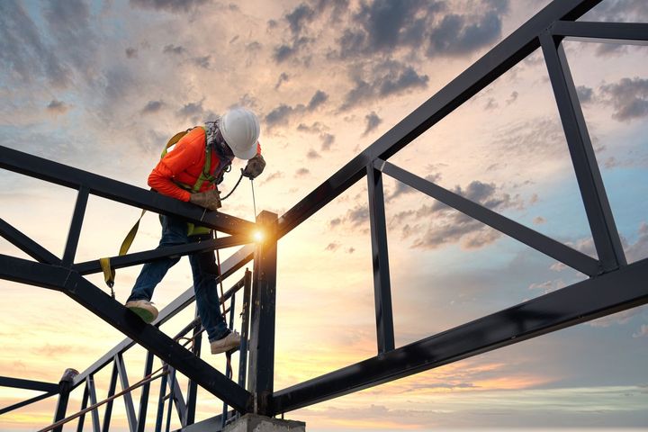 A construction worker is working on a bridge at sunset.