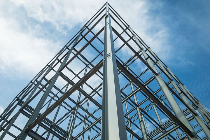 Looking up at a building under construction with a blue sky in the background.