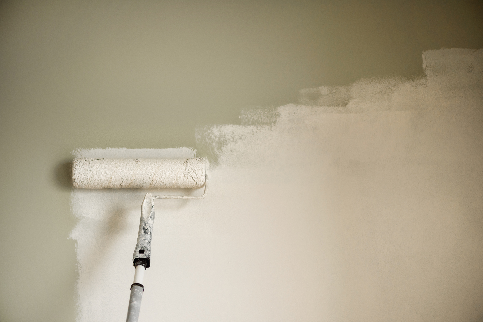 Painting a wall with a paint roller.