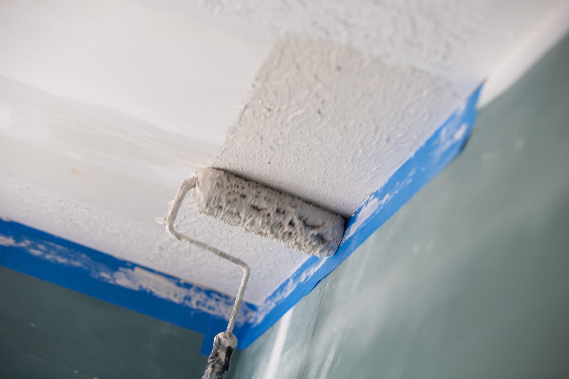 Painting a ceiling with a roller.
