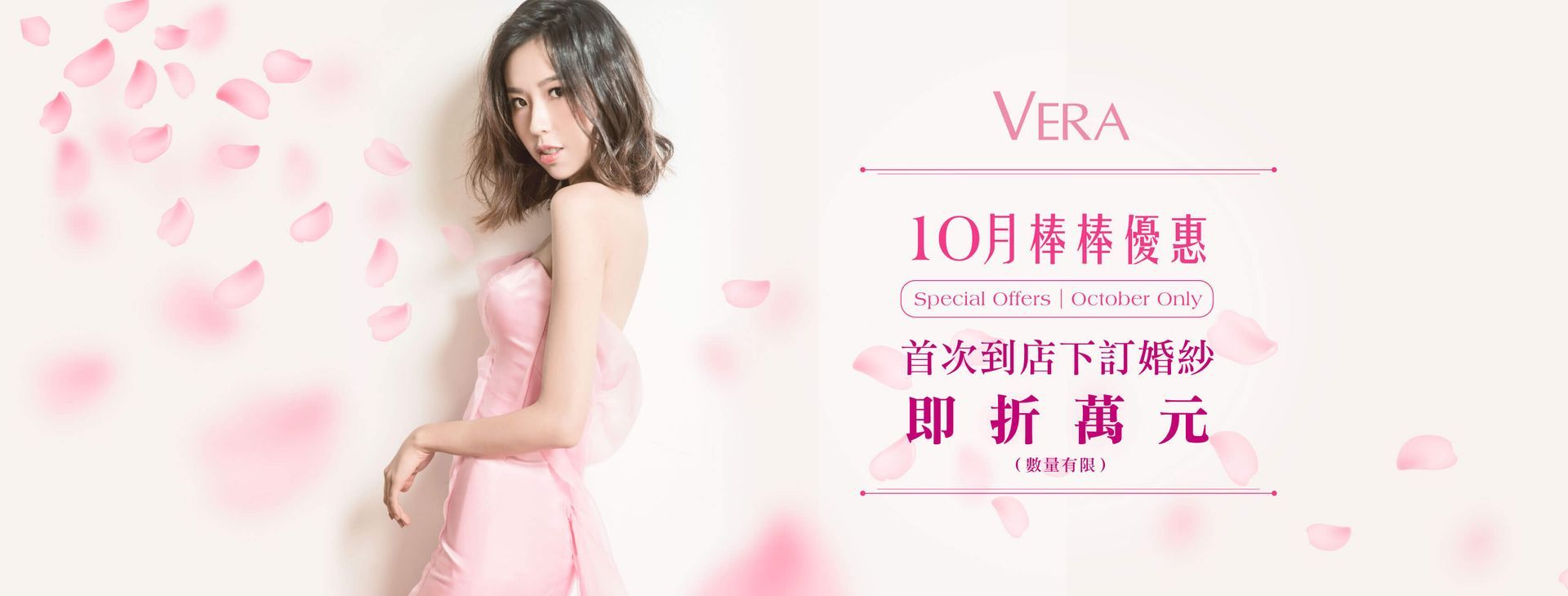 A woman in a pink dress is standing in front of a wall surrounded by pink petals.