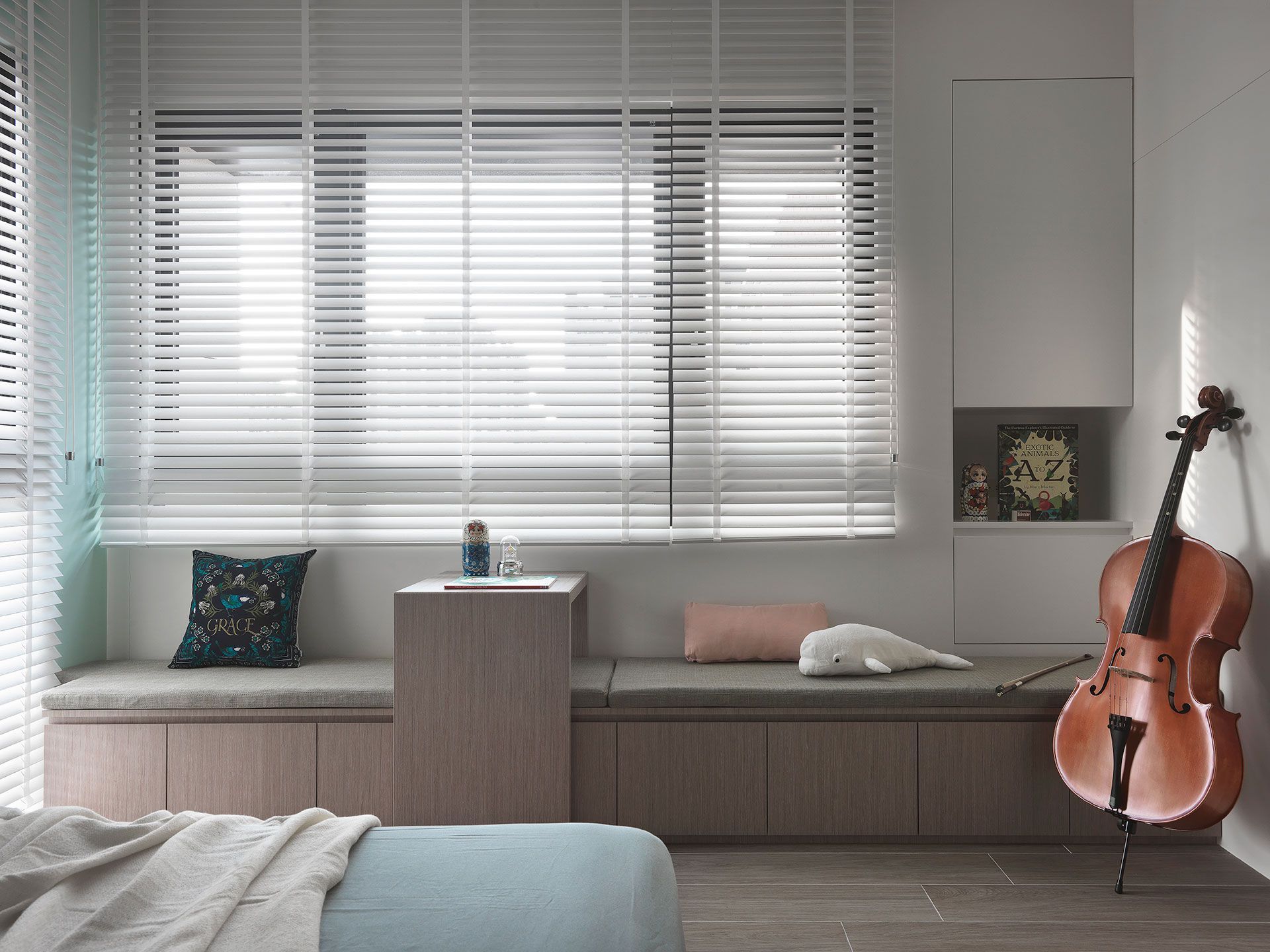 A cello is sitting on a window sill in a living room.
