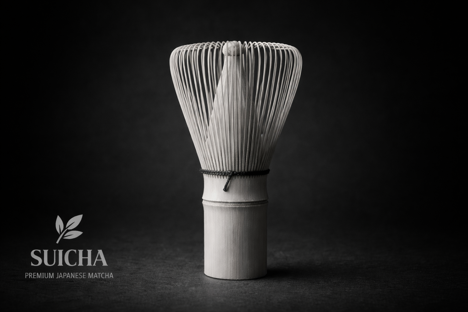 Bamboo matcha whisk, pale wood color, against a dark gray background.
