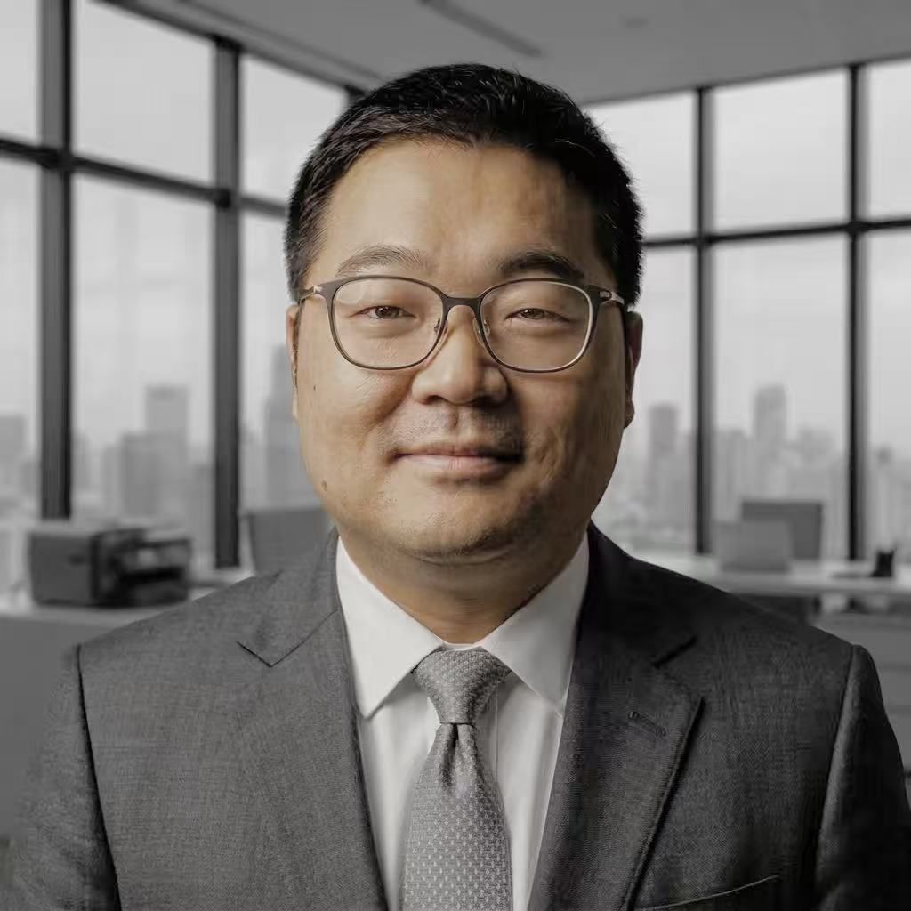 Man in suit and glasses smiles, office setting, cityscape background.