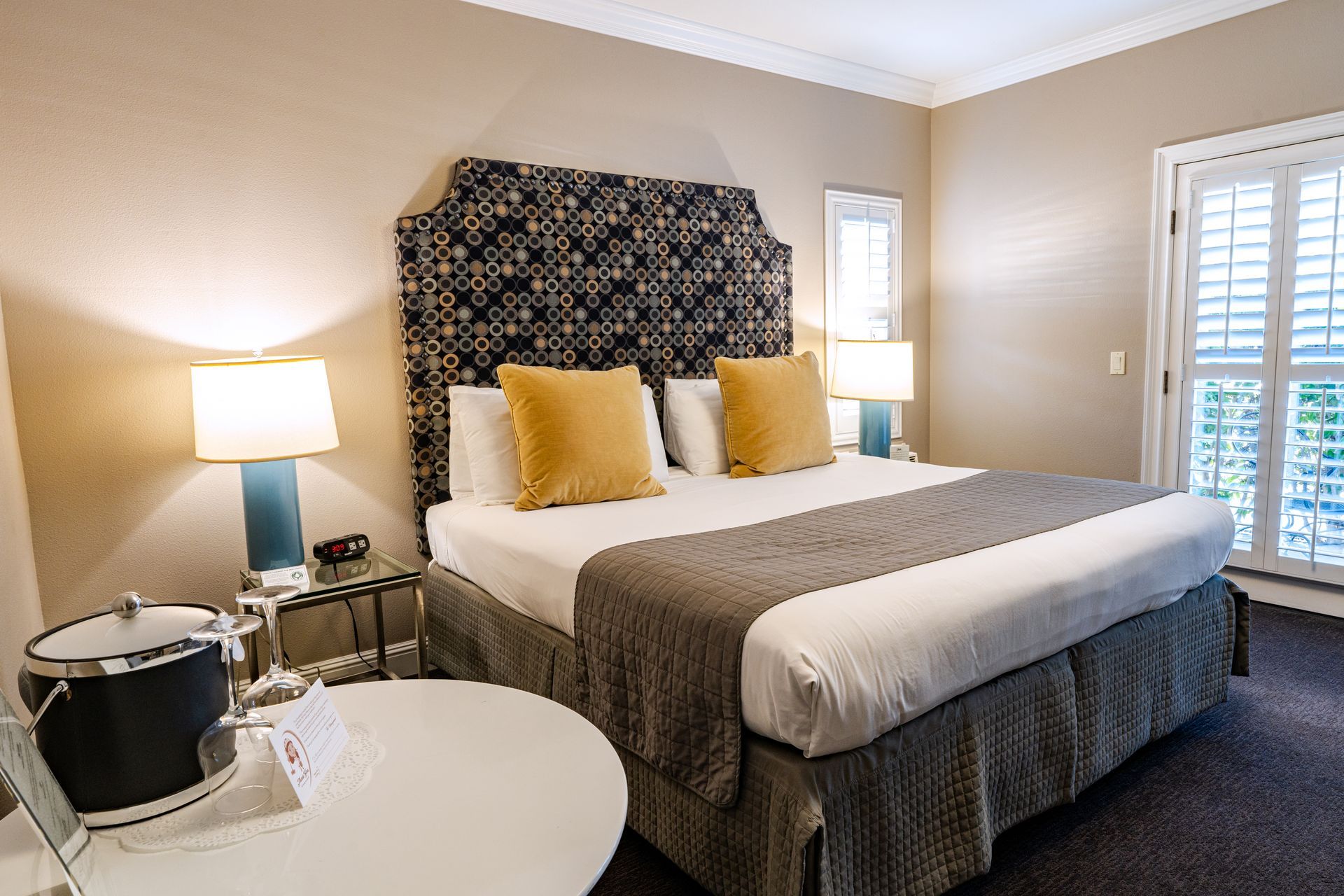 Hotel bedroom with a king bed, bedside tables, lamps, and a round table.