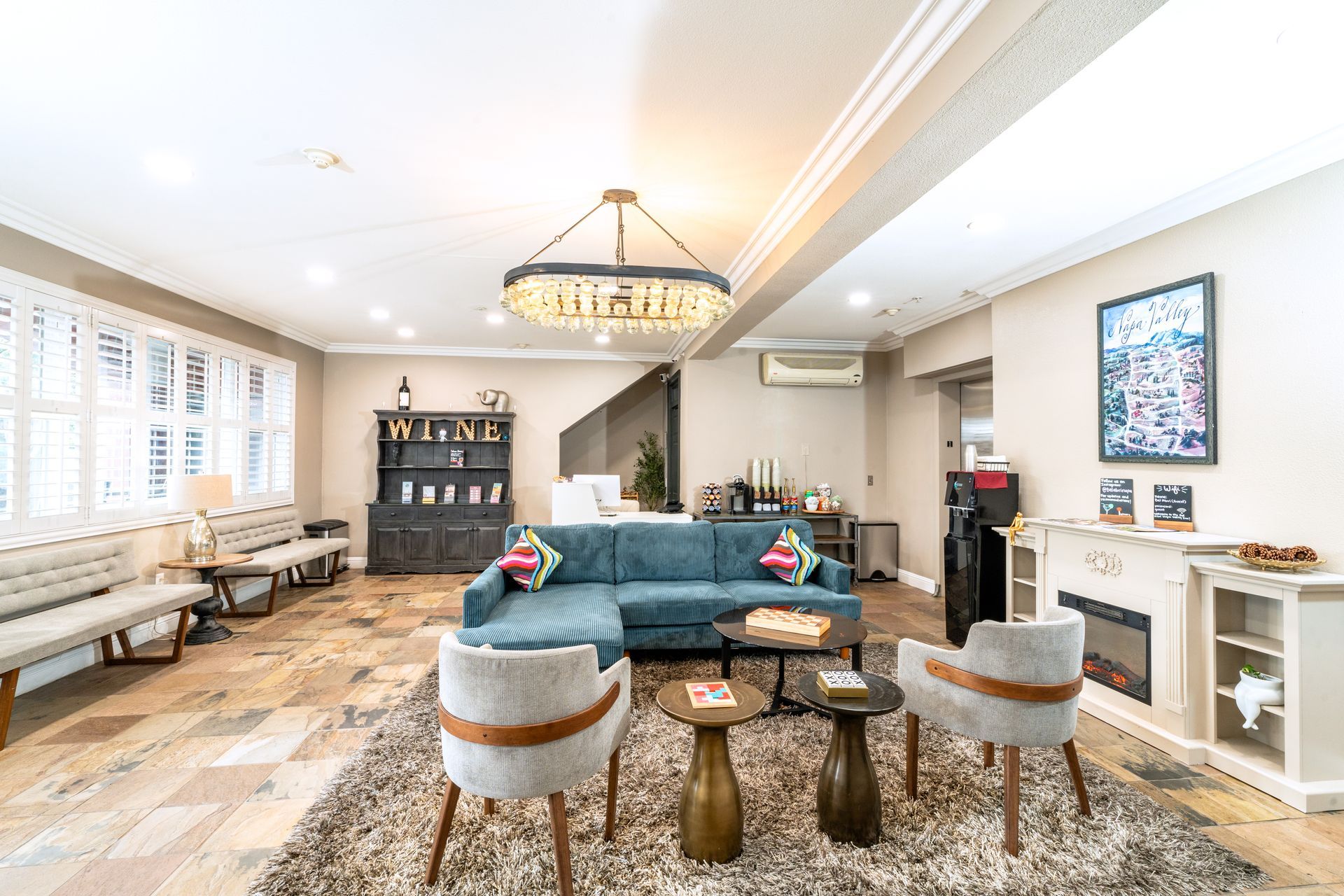 Hotel bedroom with a king bed, patterned headboard, bedside tables, and a round table.